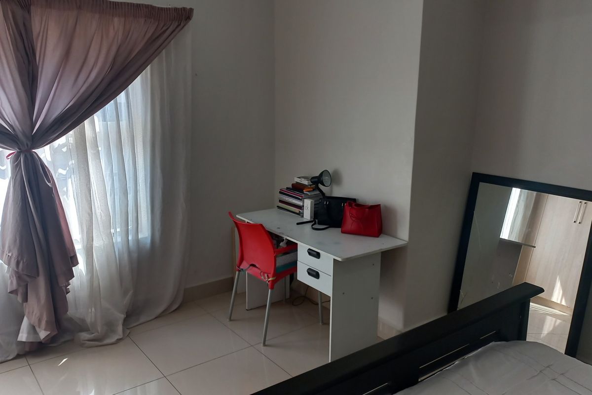 A bedroom featuring tiled flooring and a large window with curtains, providing natural light to the space.