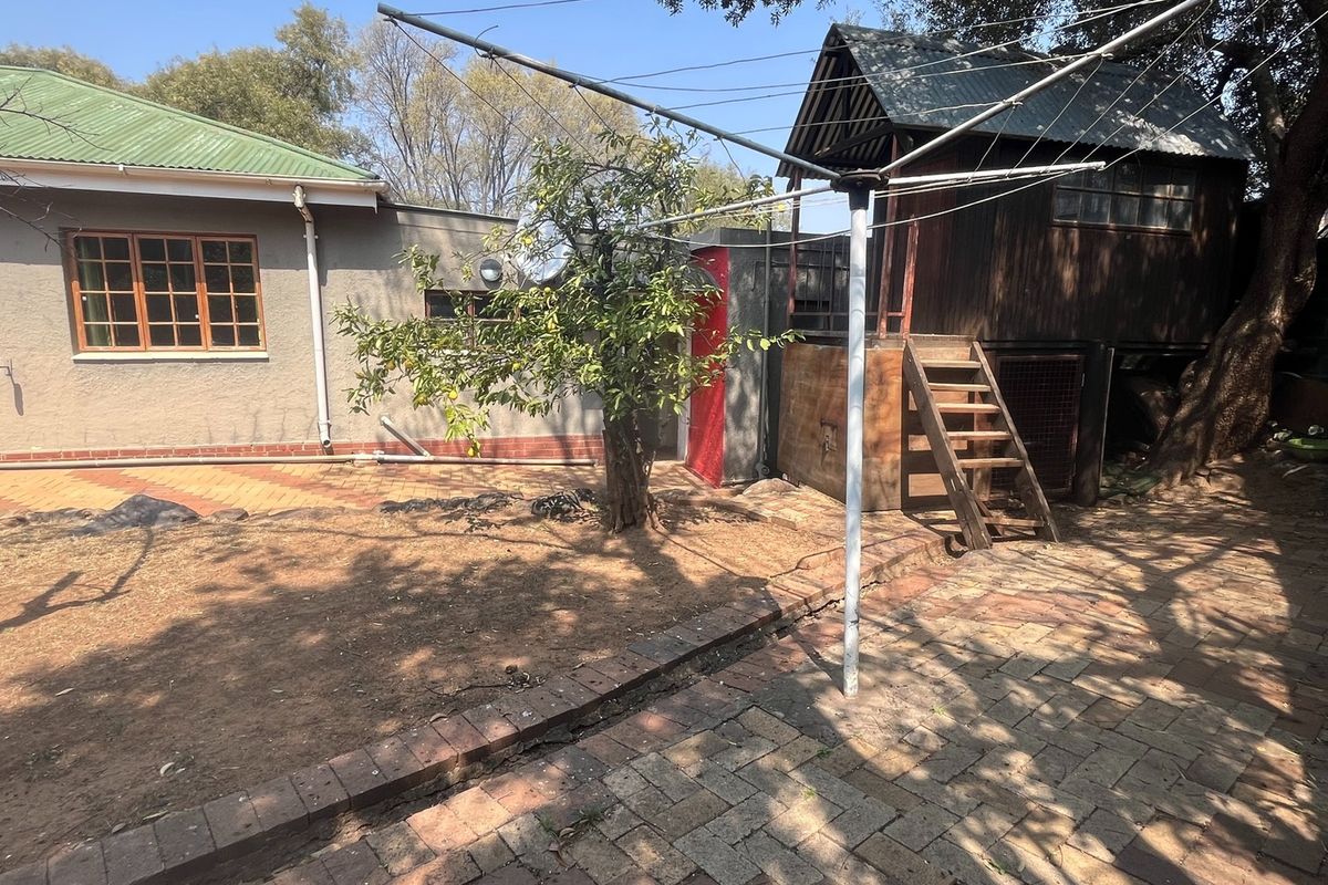 Rear garden area featuring paved patio space, a mature tree, and a raised wooden play structure.