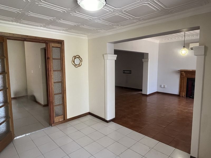 Spacious open-plan living area featuring tiled flooring, decorative ceiling panels, and a traditional wooden fireplace surround.