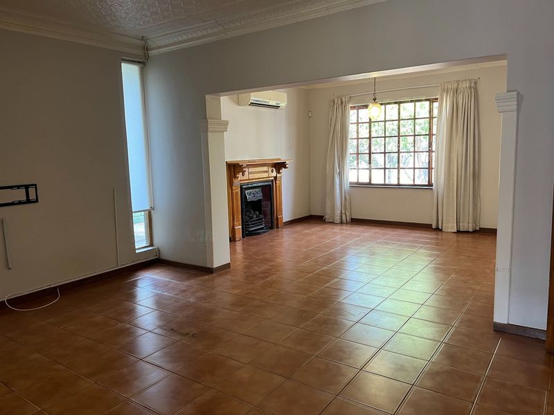 Spacious open-plan living area featuring ceramic floor tiles, a traditional fireplace with a wooden mantel, and a wall-mounted air conditioning unit.