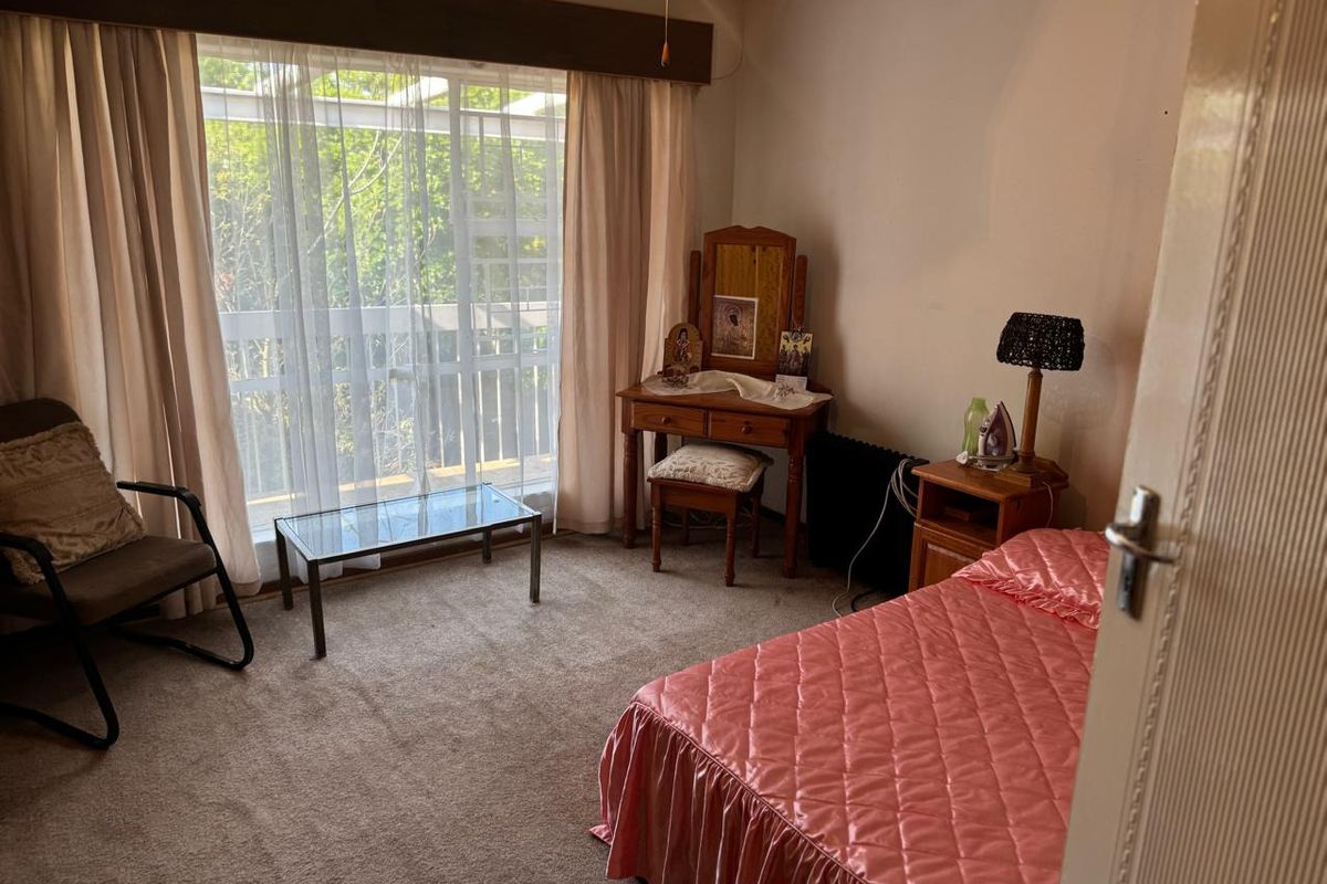 A carpeted bedroom featuring a large window with curtains and access to an outdoor area.