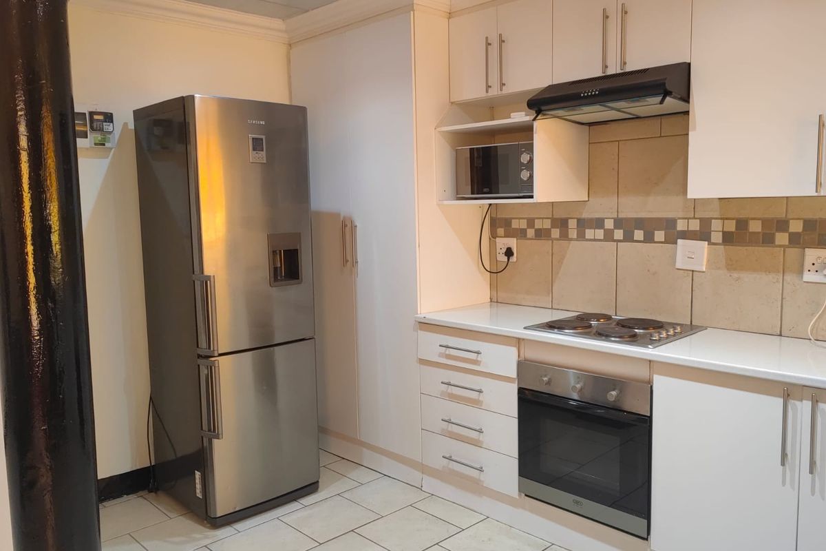 Modern kitchen featuring white cabinetry, tiled backsplash, built-in oven, electric hob, and extractor fan with tiled flooring.