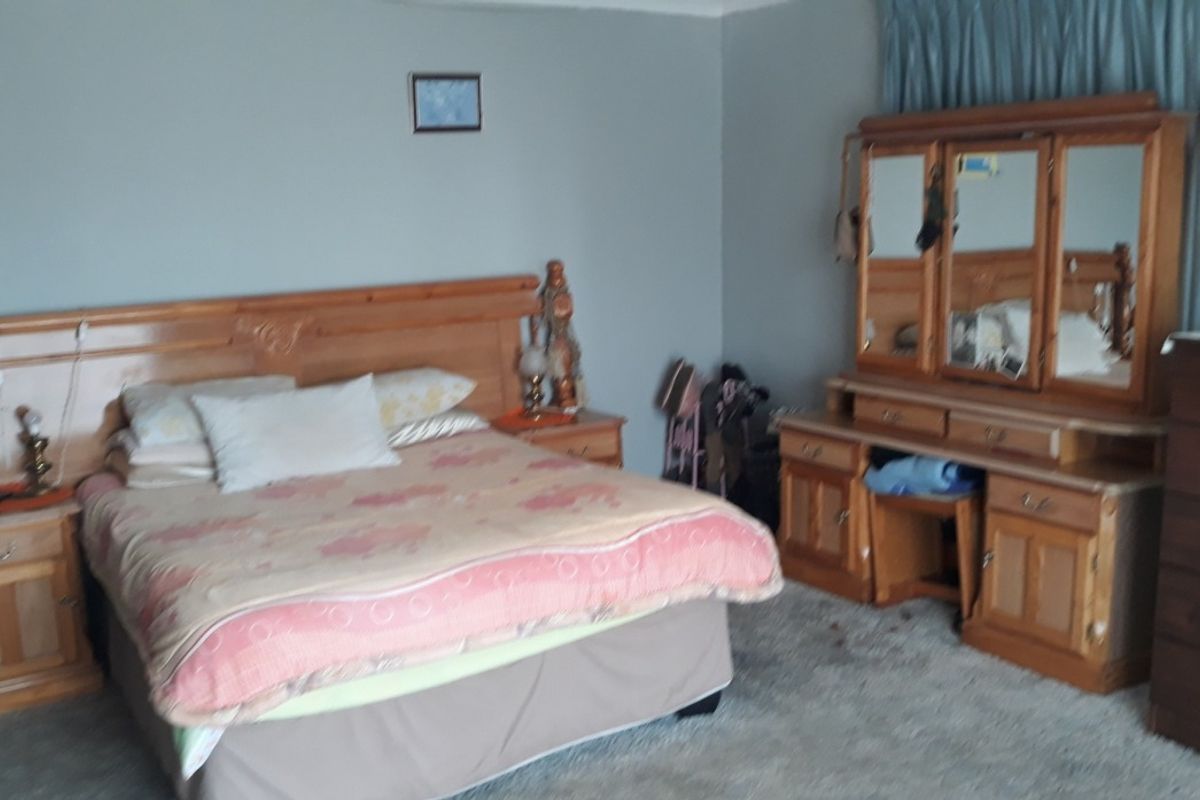 A spacious bedroom featuring neutral wall tones, carpeted flooring, and a classic layout suitable for comfortable living.