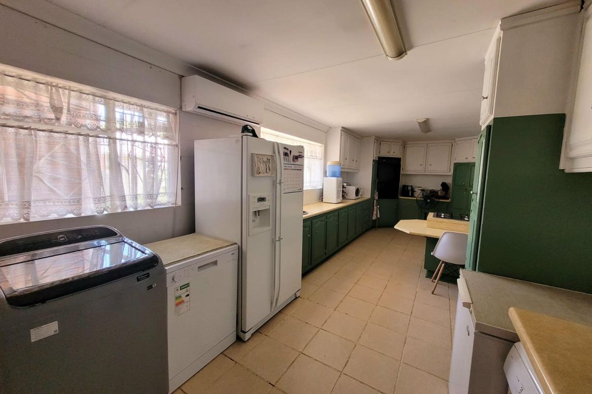 Spacious kitchen featuring extensive built-in cabinetry, laminate countertops, and tiled flooring, offering a functional layout with integrated appliance space.