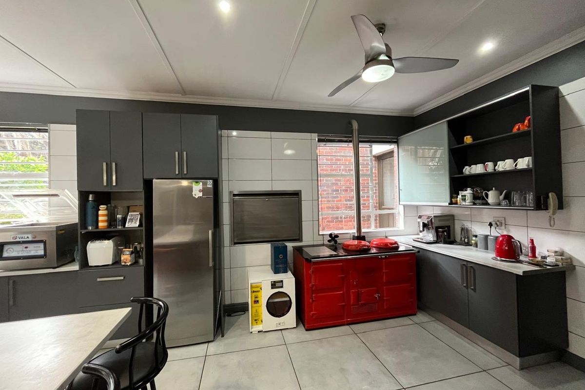 Modern kitchen featuring dark grey cabinetry, tiled flooring, a built-in braai, and a distinctive red range cooker, offering a functional and stylish cooking space.