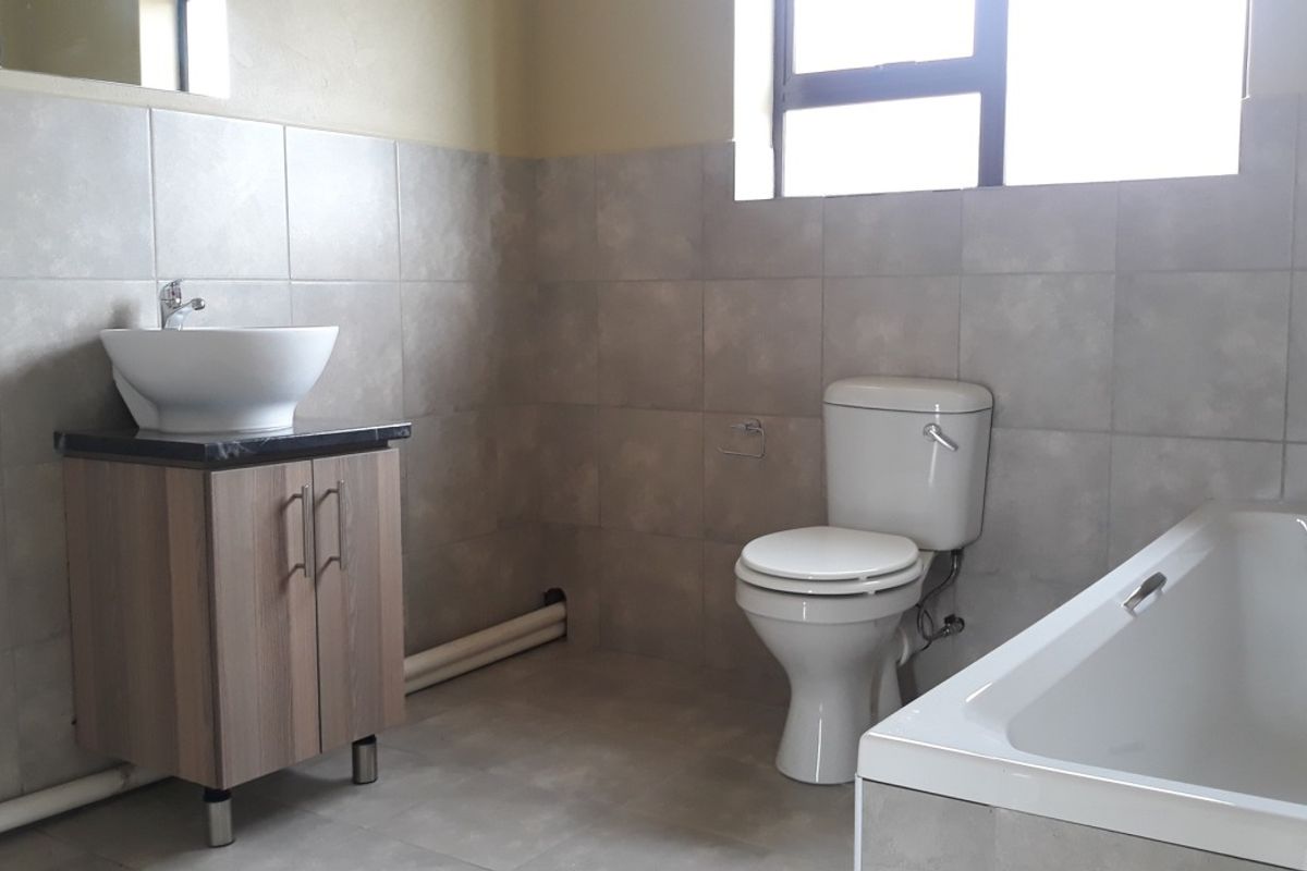 A functional bathroom featuring a vanity with a vessel sink, a standard toilet, and a bathtub with tiled surrounds.