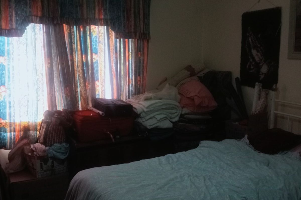 A bedroom featuring a window with curtain rods and a ceiling light fixture, currently used as a living space.