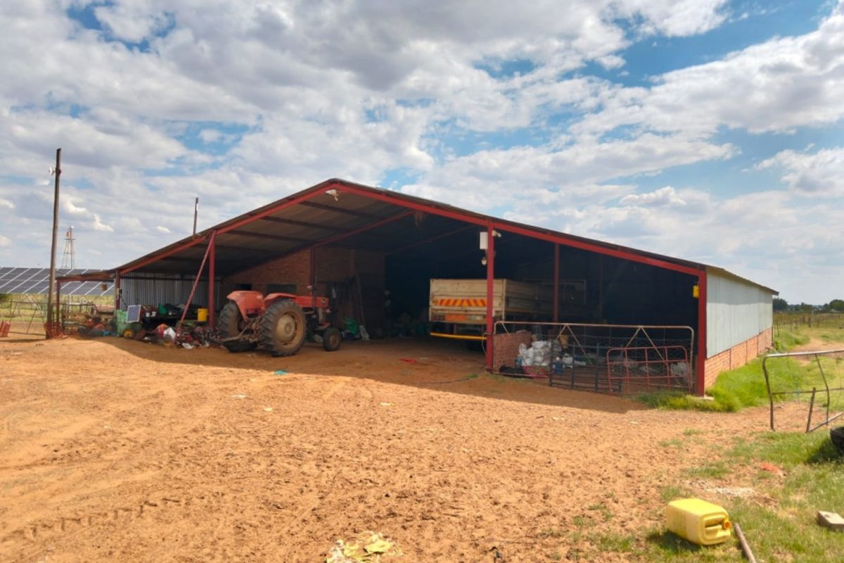 A large, open-sided farm utility barn featuring a steel frame and corrugated metal roof, suitable for equipment storage and agricultural operations.