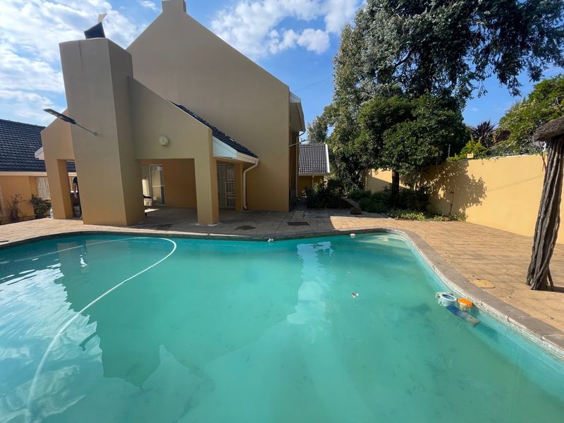 Outdoor pool area featuring a paved patio, built-in fireplace, and boundary wall, providing a private space for relaxation and entertainment.