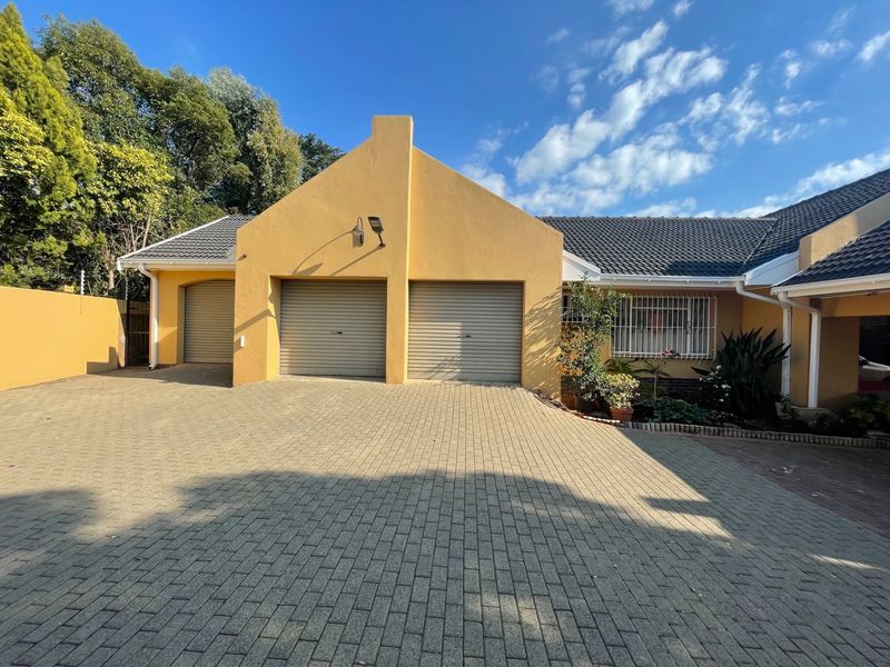 Front view of the property featuring a double garage, paved driveway, and well-maintained exterior facade with tiled roofing.