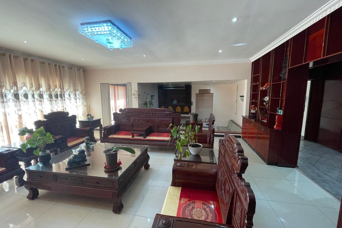 Spacious living room featuring large-format floor tiles, recessed ceiling lighting, and extensive built-in wooden cabinetry for storage and display.
