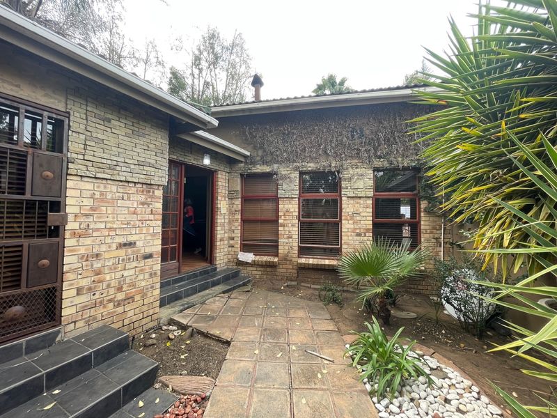 Rear exterior view featuring face brick and stone cladding, tiled patio area, and timber framed windows with integrated security features.