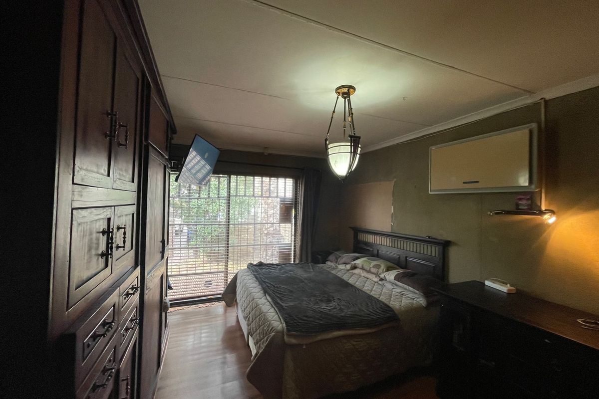A bedroom featuring laminate flooring, a built-in wardrobe, an air conditioning unit, and a sliding glass door leading to the exterior.
