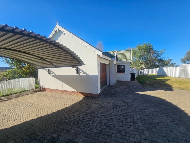 Front exterior view of the townhouse featuring a paved driveway, a covered carport, a single garage, and a white picket fence.