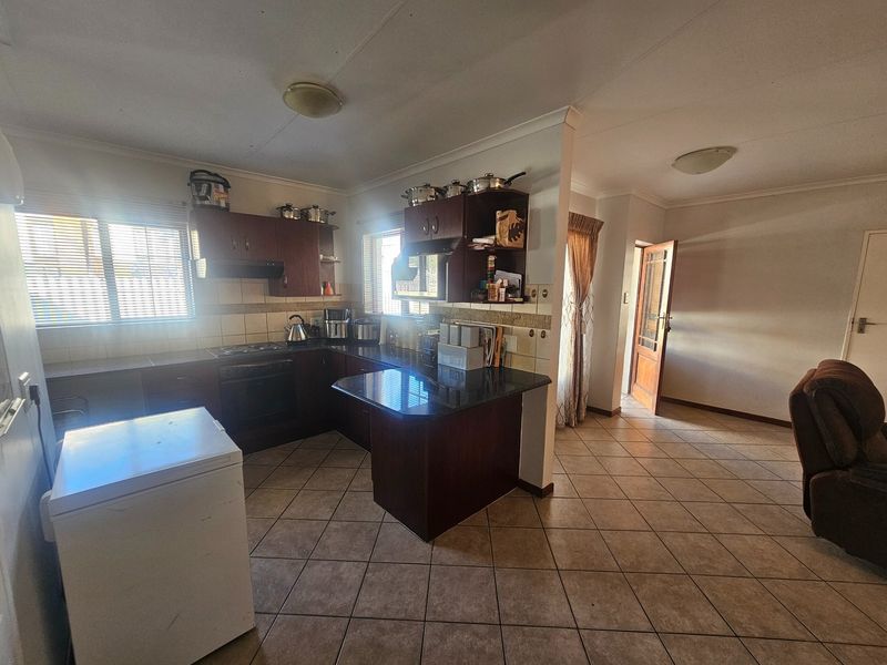 A functional kitchen featuring dark wood cabinetry, granite countertops, built-in oven and hob, and tiled flooring, offering a practical layout for daily use.