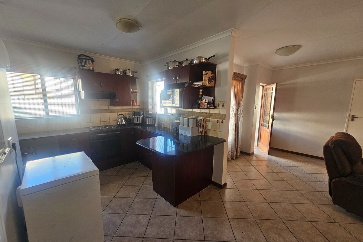 A functional kitchen featuring dark wood cabinetry, granite countertops, built-in oven and hob, and tiled flooring, offering a practical layout for daily use.