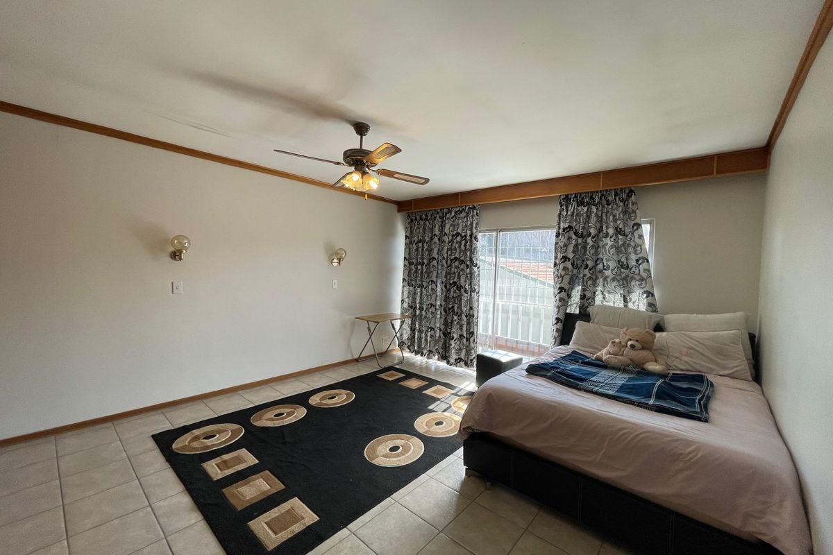 Spacious bedroom featuring tiled flooring, a ceiling fan, wall sconces, and sliding glass door access to an outdoor area.