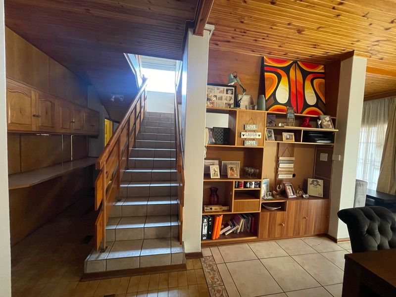 Living area featuring a tiled staircase with timber handrail, built-in cabinetry, and a timber-clad ceiling.