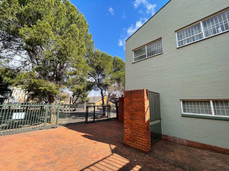 A private rear courtyard featuring brick paving, secure metal perimeter fencing, and a brick pillar, providing a functional outdoor space.