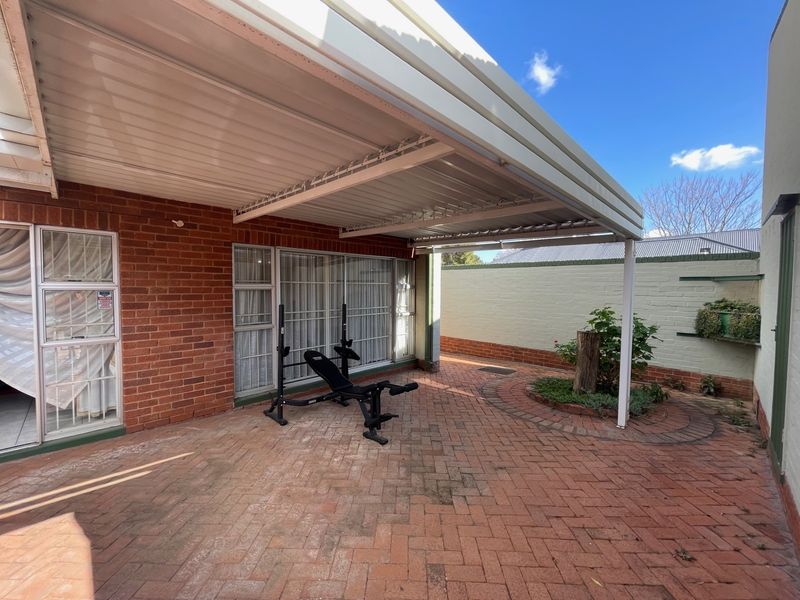 A covered outdoor patio area featuring brick paving and direct access to the interior through sliding glass doors.