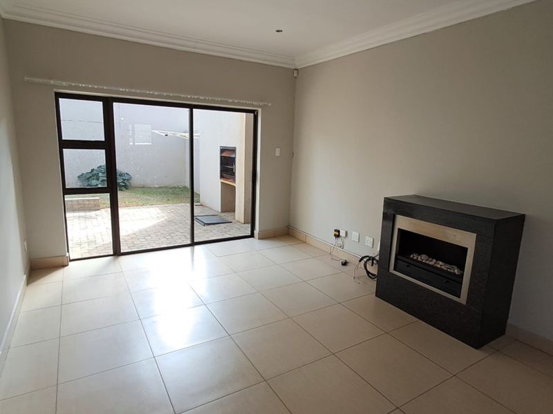 Spacious living area featuring neutral tiled flooring, a modern built-in fireplace, and large sliding glass doors providing direct access to the rear patio.