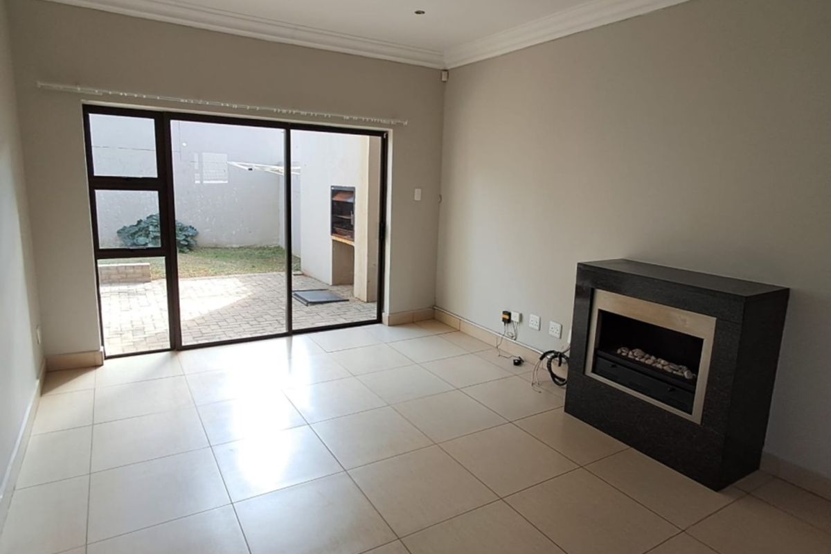 Spacious living area featuring neutral tiled flooring, a modern built-in fireplace, and large sliding glass doors providing direct access to the rear patio.