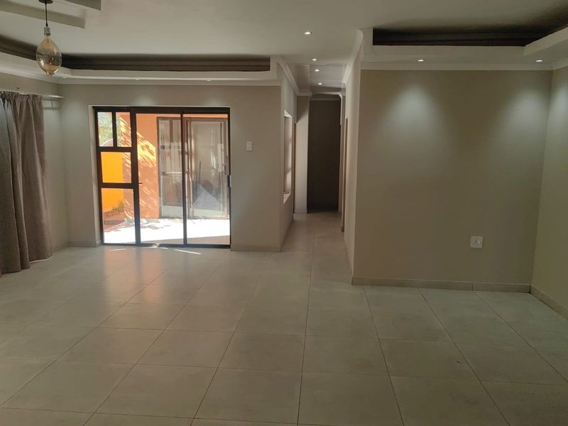 Spacious, neutral-toned living area featuring tiled flooring, recessed ceiling lighting, and a sliding glass door providing access to the exterior.