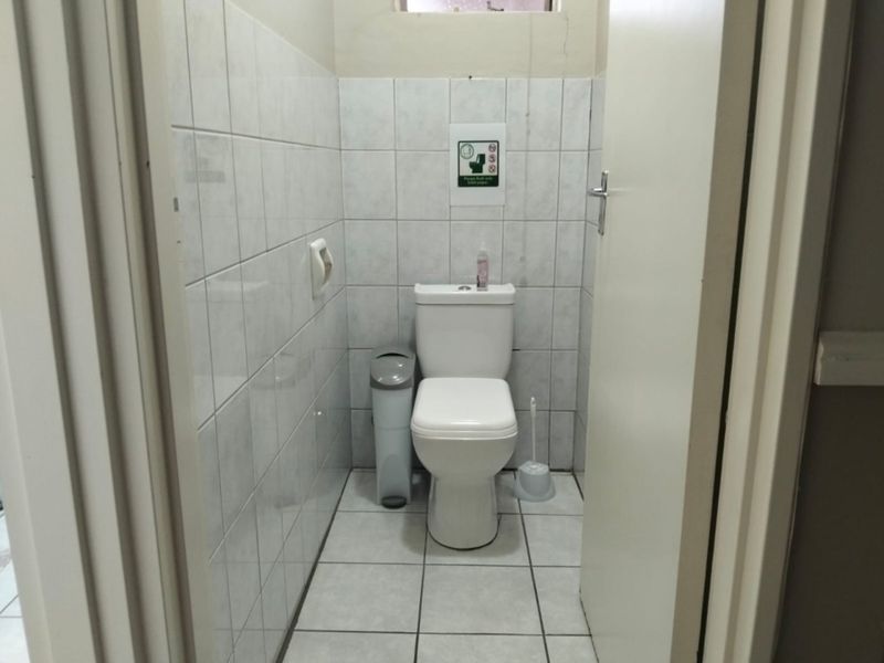 A small, functional guest bathroom featuring white ceramic wall and floor tiles with a standard toilet suite.