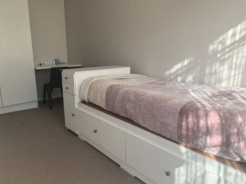 A bedroom featuring carpet flooring and a built-in wardrobe, showing a visible crack on the wall surface.