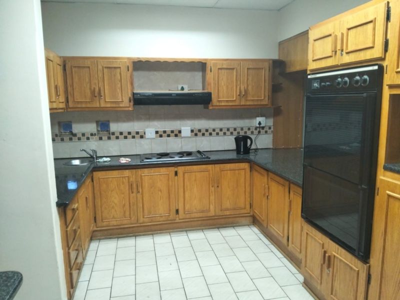 A functional kitchen featuring traditional wooden cabinetry, granite countertops, a built-in oven, and an electric hob with an extractor fan.