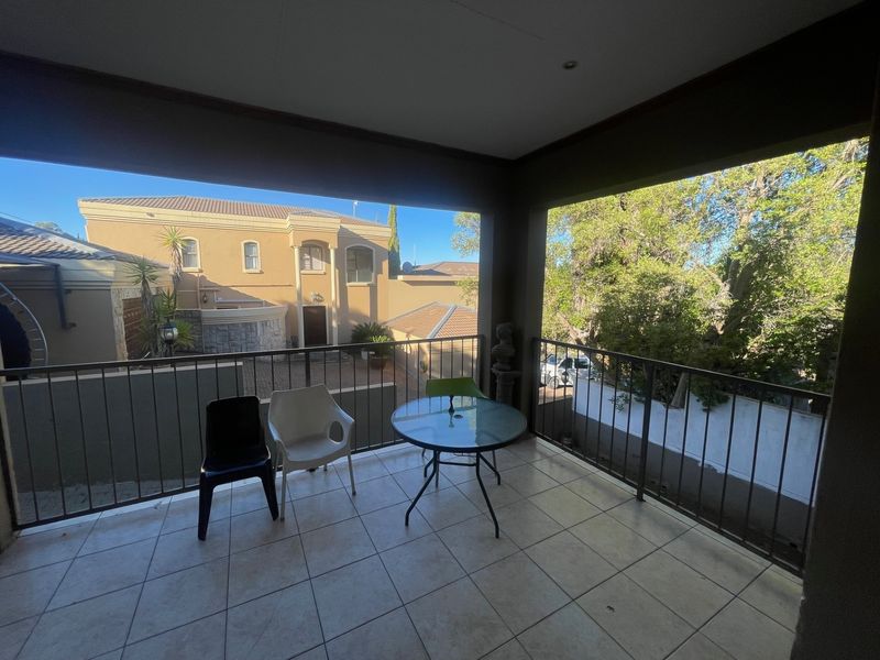 A covered balcony featuring tiled flooring and a metal balustrade, offering an elevated view of the surrounding residential property.