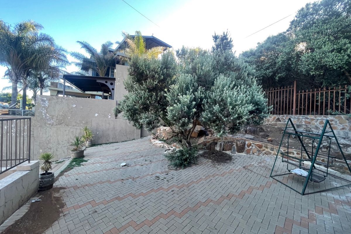 Rear garden area featuring paved patio space, stone retaining walls, and perimeter fencing, requiring maintenance to the boundary wall and paving surfaces.