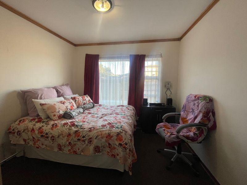 A standard bedroom featuring neutral walls, a window with curtains, and ceiling cornice detailing.