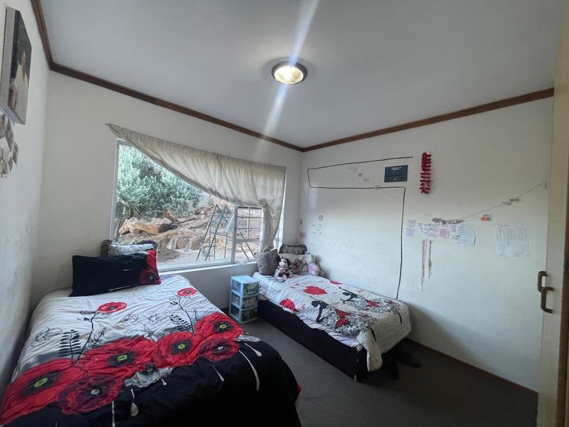 A functional bedroom featuring carpeted flooring, a large window with natural light, and neutral wall finishes.