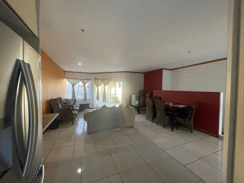 Spacious open-plan living and dining area featuring tiled flooring, recessed lighting, and a sliding glass door leading to the outdoor space.