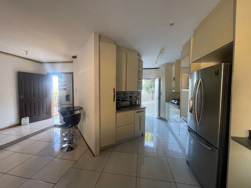A functional kitchen area featuring built-in cabinetry, tiled flooring, and integrated appliances, providing a practical layout for daily cooking and meal preparation.