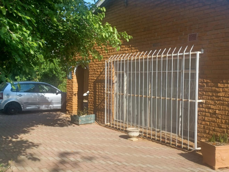 Front exterior view of a face brick house featuring a paved driveway and security bars over the windows.