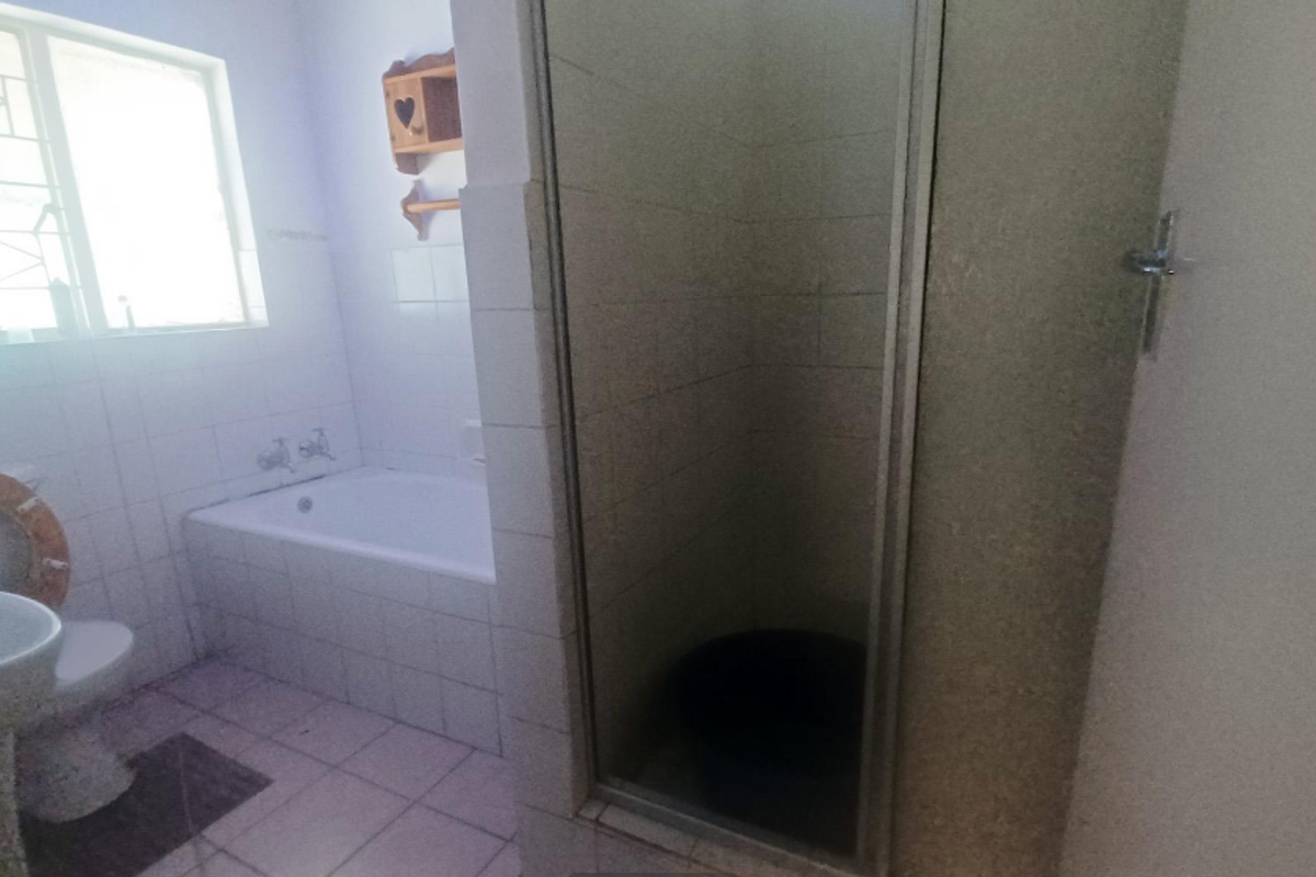 A functional bathroom featuring a bathtub, separate shower enclosure, pedestal basin, and toilet with tiled finishes throughout.