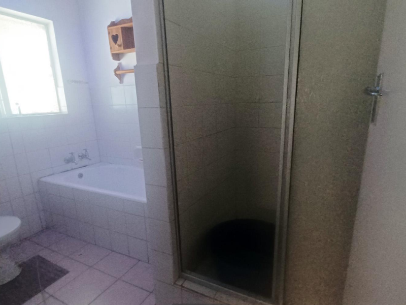 A functional bathroom featuring a bathtub, separate shower enclosure, pedestal basin, and toilet with tiled finishes throughout.