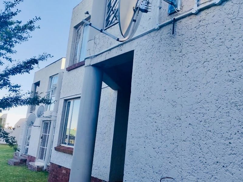 Rear elevation of the flat featuring textured plaster walls, security gates, and visible satellite dish installations.