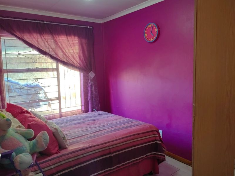 A bedroom featuring a built-in cupboard, security bars on the window, and coving detail.