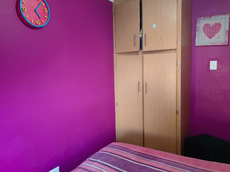 A bedroom featuring a built-in wooden wardrobe with ample storage space.
