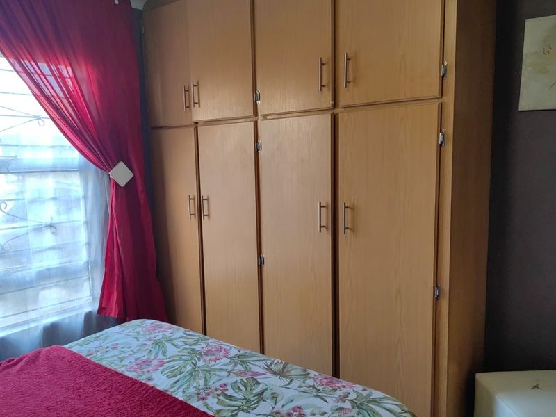 Bedroom featuring floor-to-ceiling wooden built-in cupboards and a window fitted with security bars.