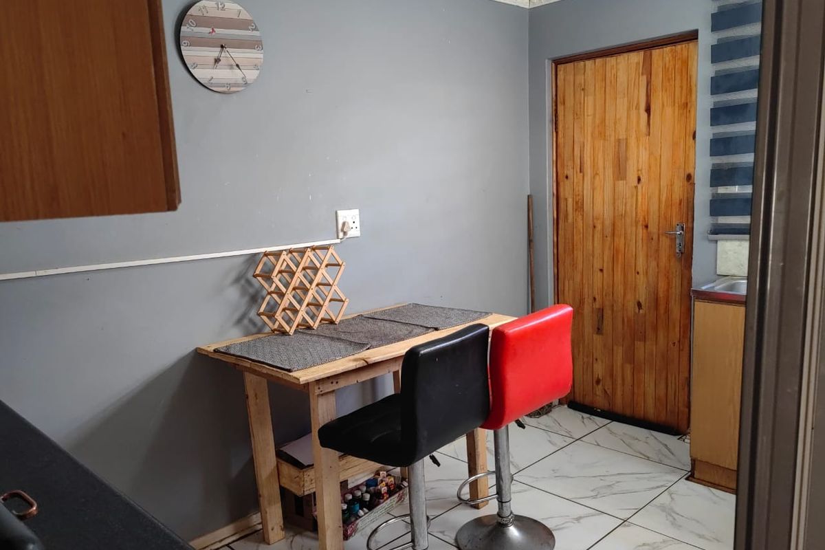 A kitchen area featuring tiled flooring, crown molding, and a wooden door, with visible surface-mounted electrical wiring.
