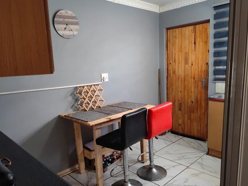 A kitchen area featuring tiled flooring, crown molding, and a wooden door, with visible surface-mounted electrical wiring.