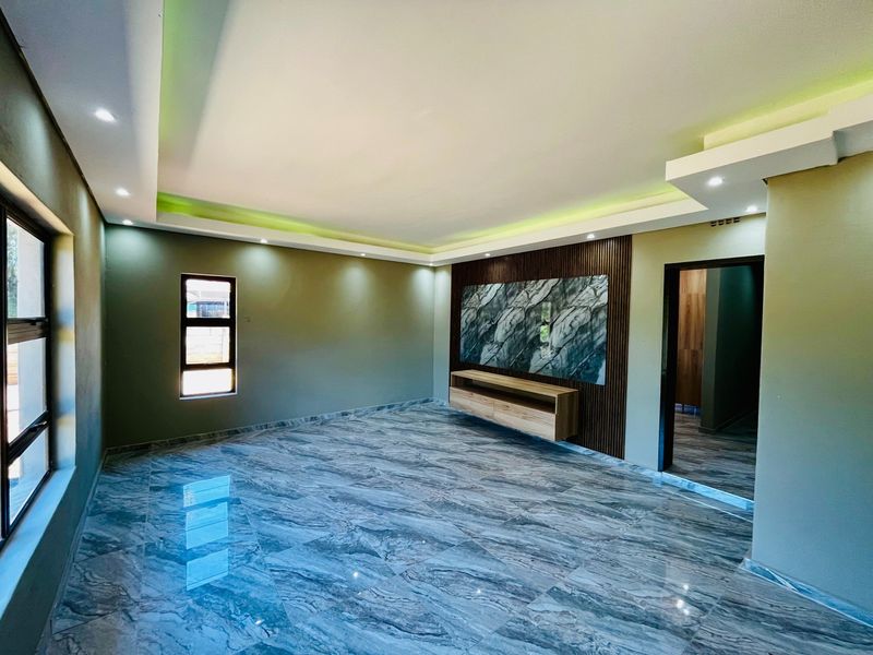 Modern living room featuring polished marble-effect floor tiles, recessed cove lighting, and a custom built-in media unit with slatted wood and marble accents.