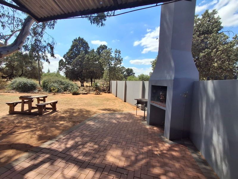 Covered outdoor patio area featuring a built-in braai, brick paving, and direct access to the garden space.