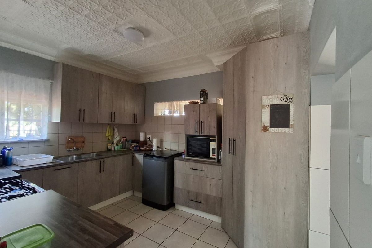 A functional kitchen featuring modern wood-look cabinetry, tiled flooring, and a textured ceiling, providing ample storage and workspace.