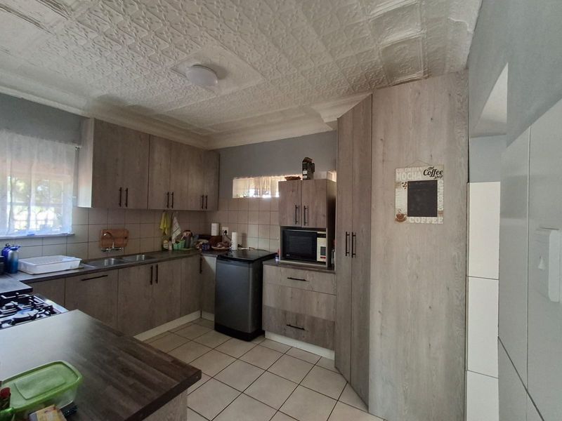 A functional kitchen featuring modern wood-look cabinetry, tiled flooring, and a textured ceiling, providing ample storage and workspace.