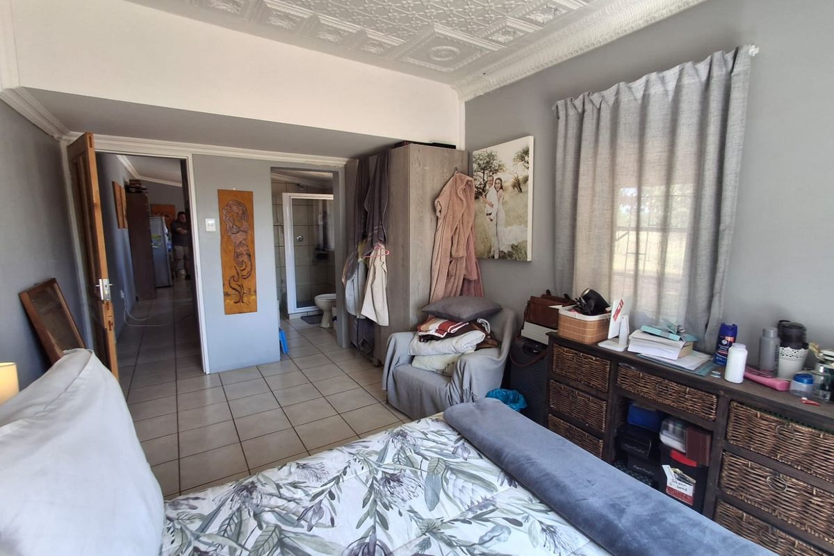 A bedroom featuring tiled flooring, a decorative pressed metal ceiling, and an en-suite bathroom, offering a functional layout with built-in storage.
